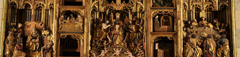 Retablo dorado con escenas religiosas talladas y figuras en relieve; estructura gótica con hornacinas y detalles calados.